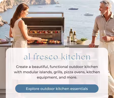 Two adults preparing a meal at a contemporary outdoor kitchen overlooking the ocean.